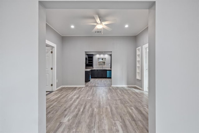 unfurnished living room with sink, ceiling fan, and light hardwood / wood-style flooring