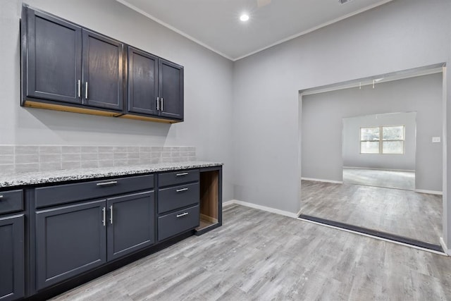 kitchen featuring dark brown cabinetry, ornamental molding, light stone countertops, and light hardwood / wood-style floors