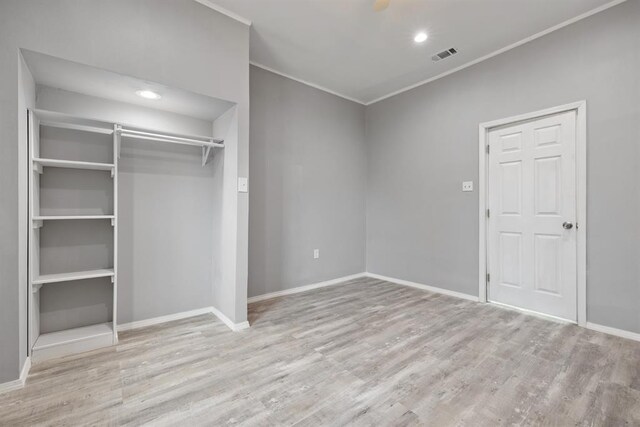 unfurnished bedroom with crown molding and light wood-type flooring