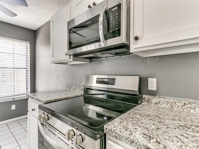 kitchen with white cabinetry, appliances with stainless steel finishes, a textured ceiling, and light tile patterned floors