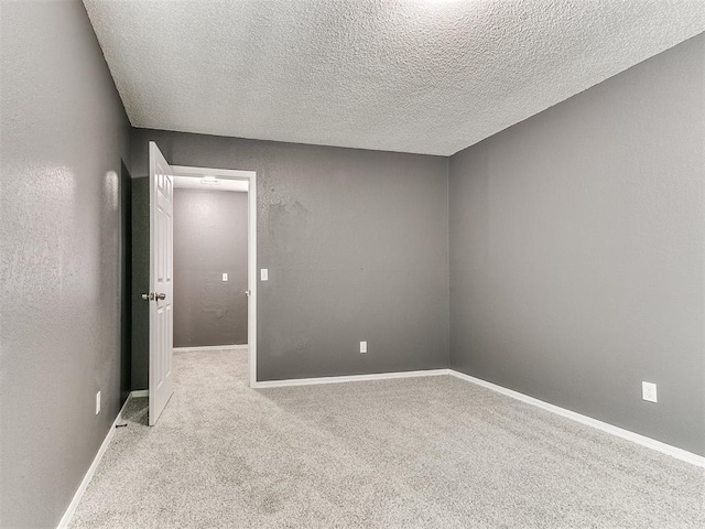 empty room with light colored carpet and a textured ceiling