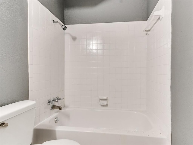 bathroom featuring tiled shower / bath and toilet