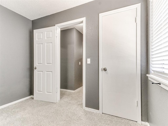 unfurnished bedroom featuring light carpet and a textured ceiling