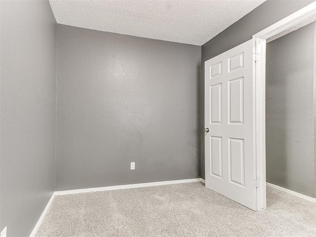 spare room featuring light colored carpet and a textured ceiling