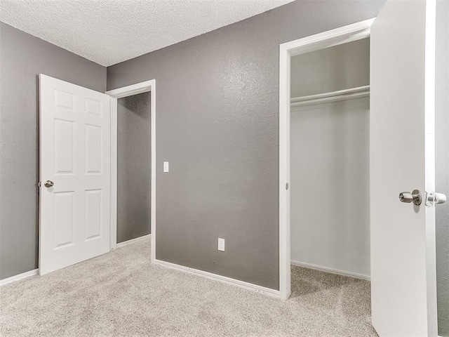 unfurnished bedroom featuring light carpet, a textured ceiling, and a closet