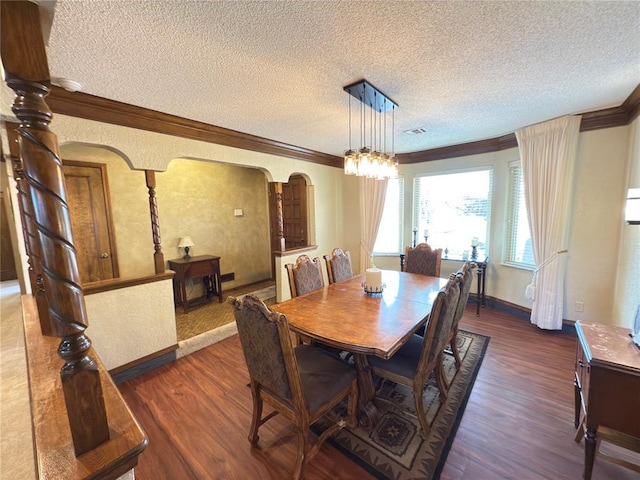 dining space with ornamental molding, dark hardwood / wood-style flooring, a textured ceiling, and a notable chandelier