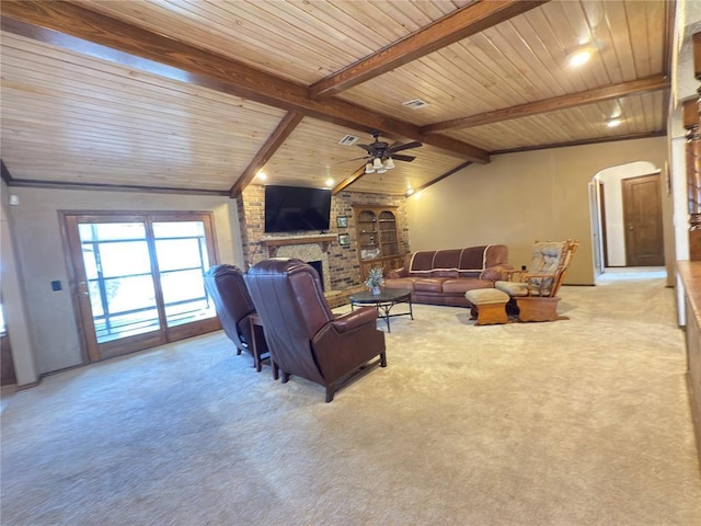 carpeted living room featuring lofted ceiling with beams, a brick fireplace, wooden ceiling, and ceiling fan