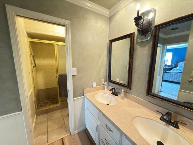 bathroom featuring vanity, a shower with door, and ornamental molding