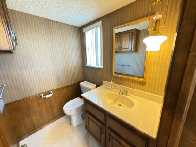 bathroom featuring vanity, a textured ceiling, and toilet