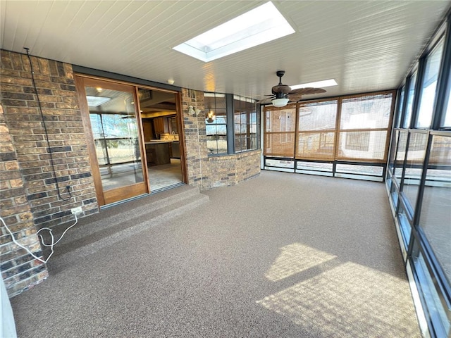 unfurnished sunroom featuring a wealth of natural light, ceiling fan, and a skylight