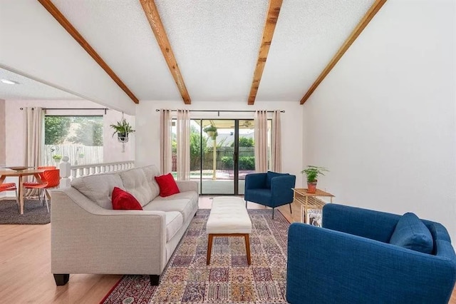 living room with vaulted ceiling with beams, wood-type flooring, and a textured ceiling