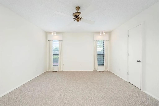 carpeted empty room with ceiling fan and a textured ceiling