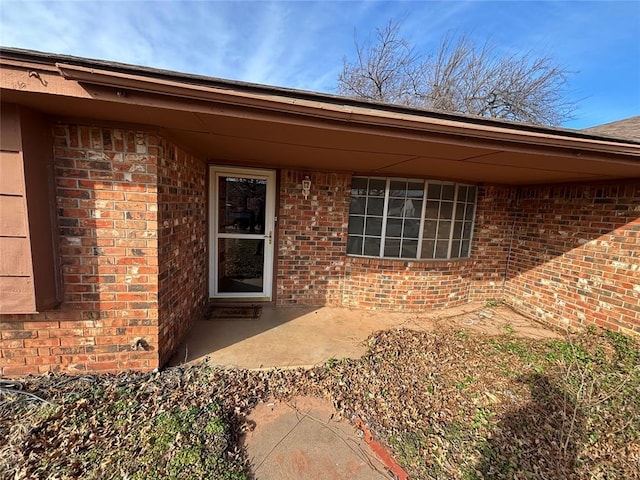 view of exterior entry with a patio area