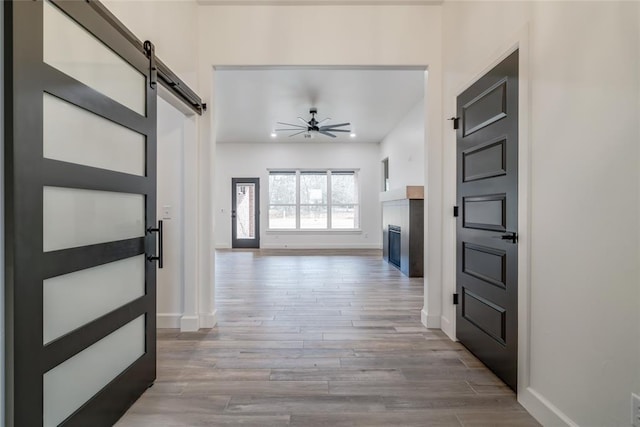 interior space featuring wood-type flooring, a barn door, and ceiling fan