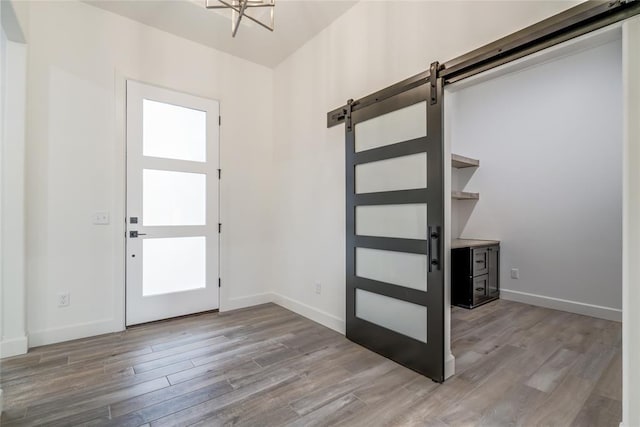 foyer entrance featuring an inviting chandelier, a barn door, and light hardwood / wood-style floors