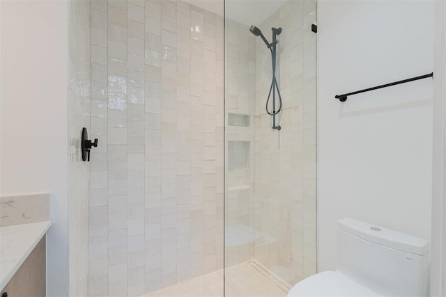 bathroom featuring vanity, a tile shower, and toilet