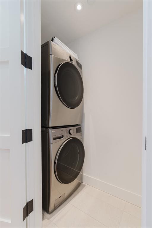 laundry room with light tile patterned floors and stacked washing maching and dryer