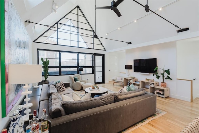 living room with ceiling fan, rail lighting, high vaulted ceiling, and light wood-type flooring