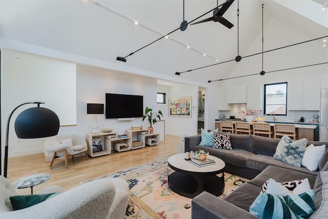 living room featuring sink, light hardwood / wood-style flooring, high vaulted ceiling, and track lighting