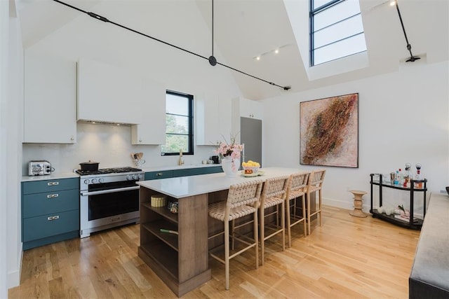 kitchen featuring high end stove, white cabinetry, a kitchen breakfast bar, a center island, and blue cabinetry