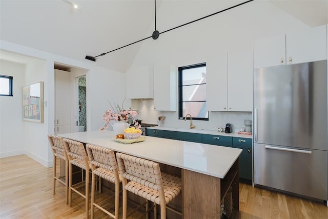 kitchen featuring white cabinetry, a center island, stainless steel fridge, and a breakfast bar