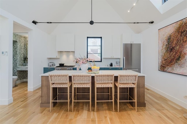 kitchen featuring white cabinetry, a kitchen island, stainless steel fridge, and a kitchen bar