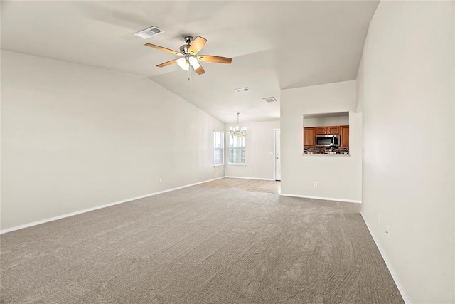 unfurnished living room featuring lofted ceiling, ceiling fan with notable chandelier, and light carpet