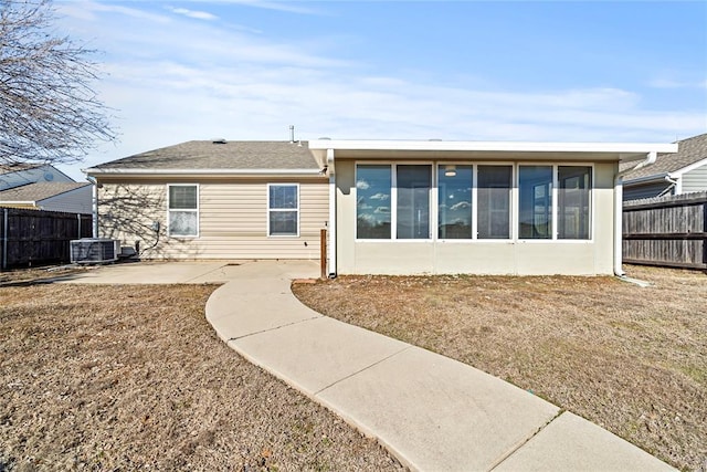 back of property with a sunroom, a lawn, central air condition unit, and a patio area