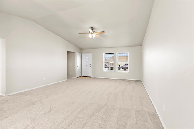 empty room with light colored carpet, ceiling fan, baseboards, and vaulted ceiling