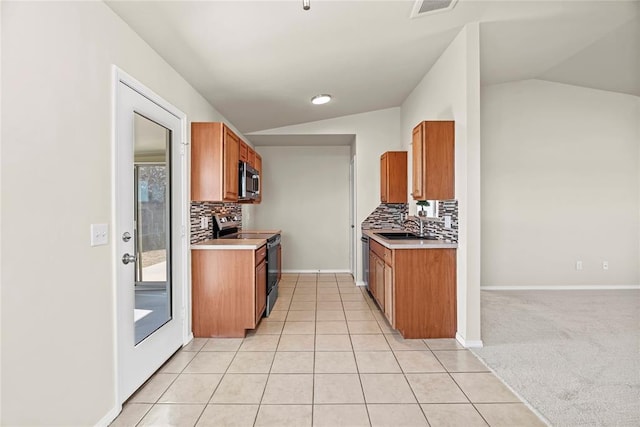 kitchen with stainless steel appliances, brown cabinets, and vaulted ceiling