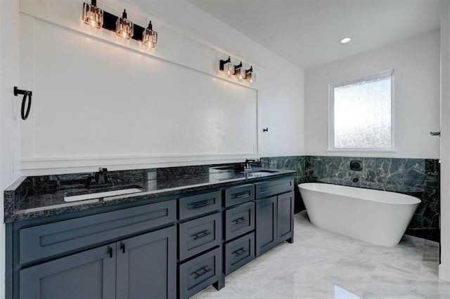 bathroom with vanity, tile walls, and a bathtub