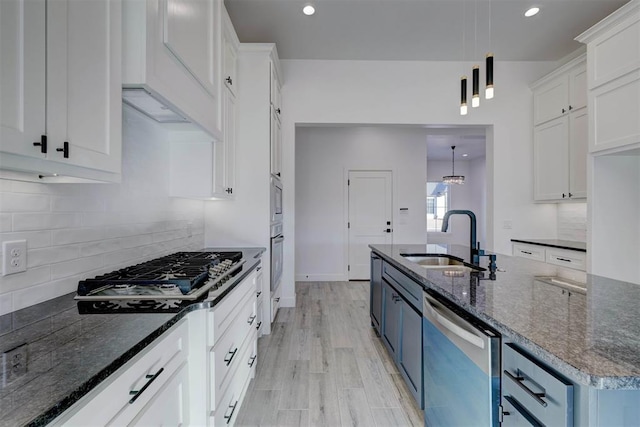 kitchen featuring pendant lighting, sink, appliances with stainless steel finishes, white cabinetry, and dark stone counters