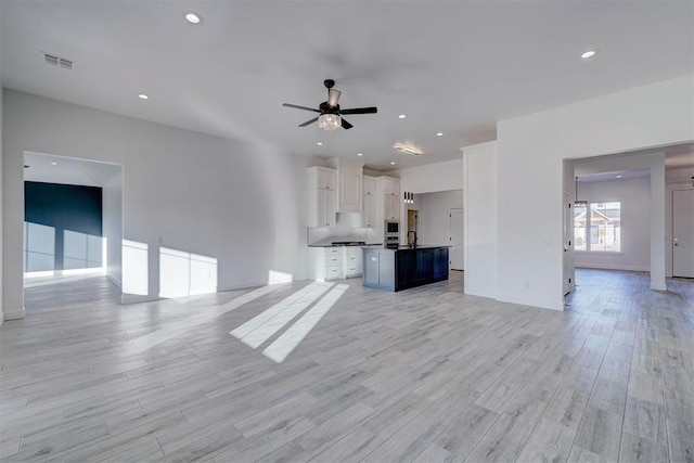 unfurnished living room featuring ceiling fan and light wood-type flooring