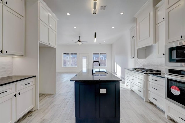 kitchen featuring white cabinetry, stainless steel appliances, sink, and a center island with sink