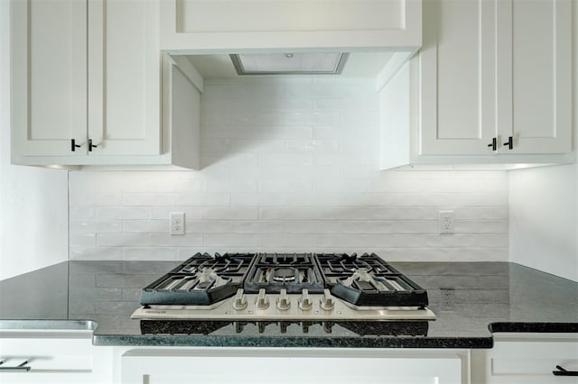 kitchen featuring white cabinets, stainless steel gas cooktop, dark stone countertops, and backsplash