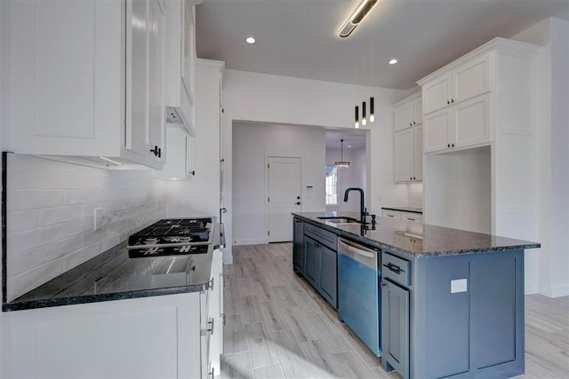 kitchen featuring pendant lighting, an island with sink, sink, white cabinets, and stainless steel appliances