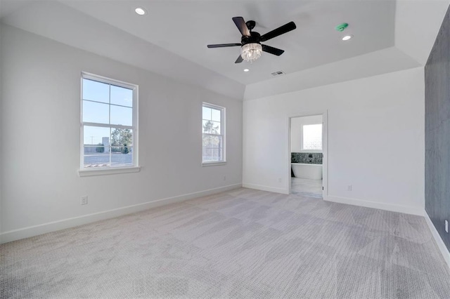 unfurnished room featuring light carpet, a tray ceiling, and ceiling fan