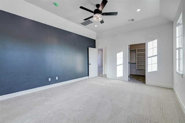 unfurnished bedroom featuring a walk in closet, carpet floors, ceiling fan, and a closet