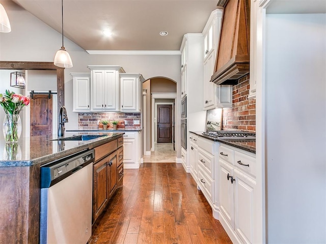 kitchen with sink, dark stone countertops, stainless steel appliances, custom range hood, and white cabinets