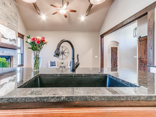 room details featuring a barn door, ceiling fan, a fireplace, and sink