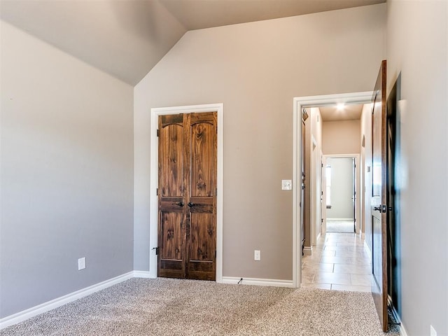 unfurnished bedroom with vaulted ceiling and light carpet