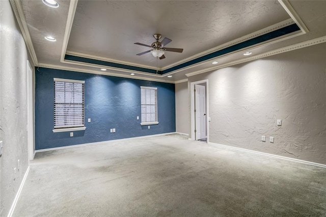 carpeted spare room featuring crown molding, a raised ceiling, and ceiling fan