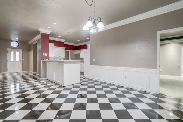 kitchen featuring white cabinets, a chandelier, hanging light fixtures, ornamental molding, and kitchen peninsula