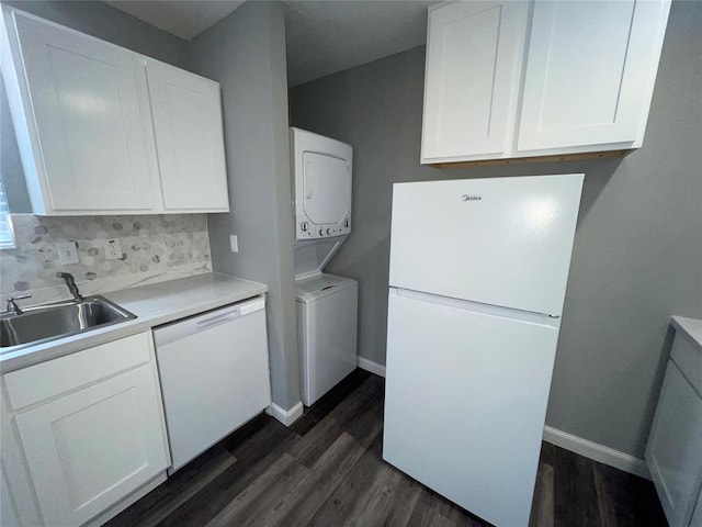 kitchen with dark wood-type flooring, sink, white cabinetry, white appliances, and stacked washing maching and dryer