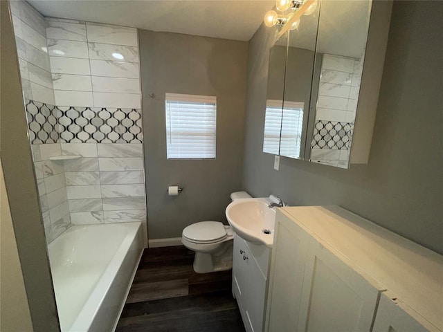 full bathroom featuring hardwood / wood-style flooring, tiled shower / bath, vanity, and toilet