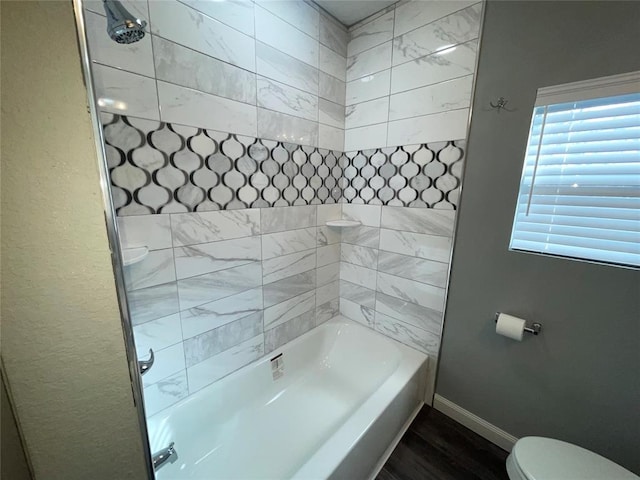 bathroom featuring hardwood / wood-style flooring, toilet, and bathtub / shower combination