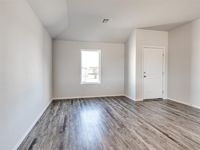 spare room with hardwood / wood-style floors and vaulted ceiling