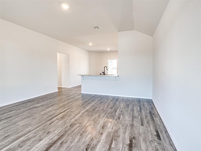 unfurnished living room with sink, dark hardwood / wood-style flooring, and vaulted ceiling