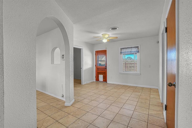 spare room with light tile patterned flooring, ceiling fan, and a textured ceiling