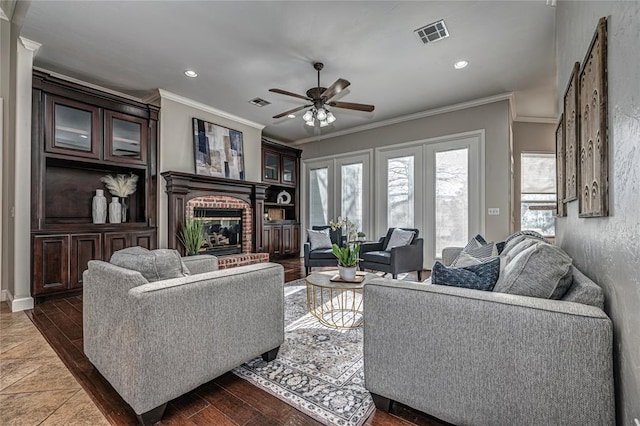 living room with dark hardwood / wood-style flooring, a fireplace, ornamental molding, and ceiling fan